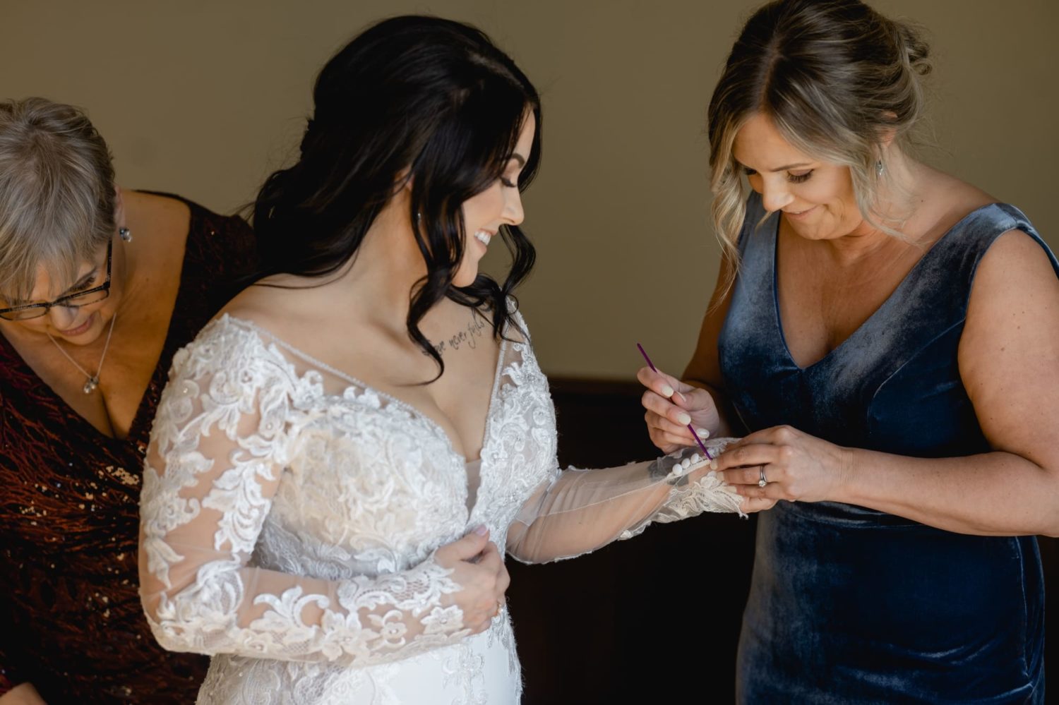 Maid of honor buttoning up wedding dress wedding at Glen Oaks country club in Des Moines Iowa