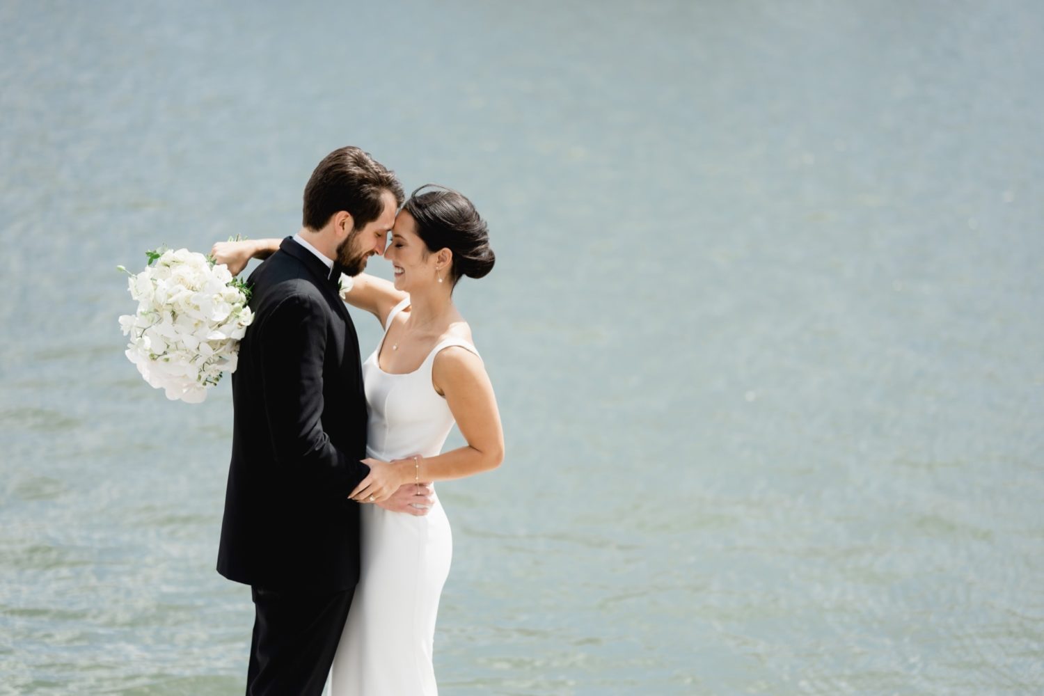 Bride and groom embracing each other by the water at the St. Louis Art Museum