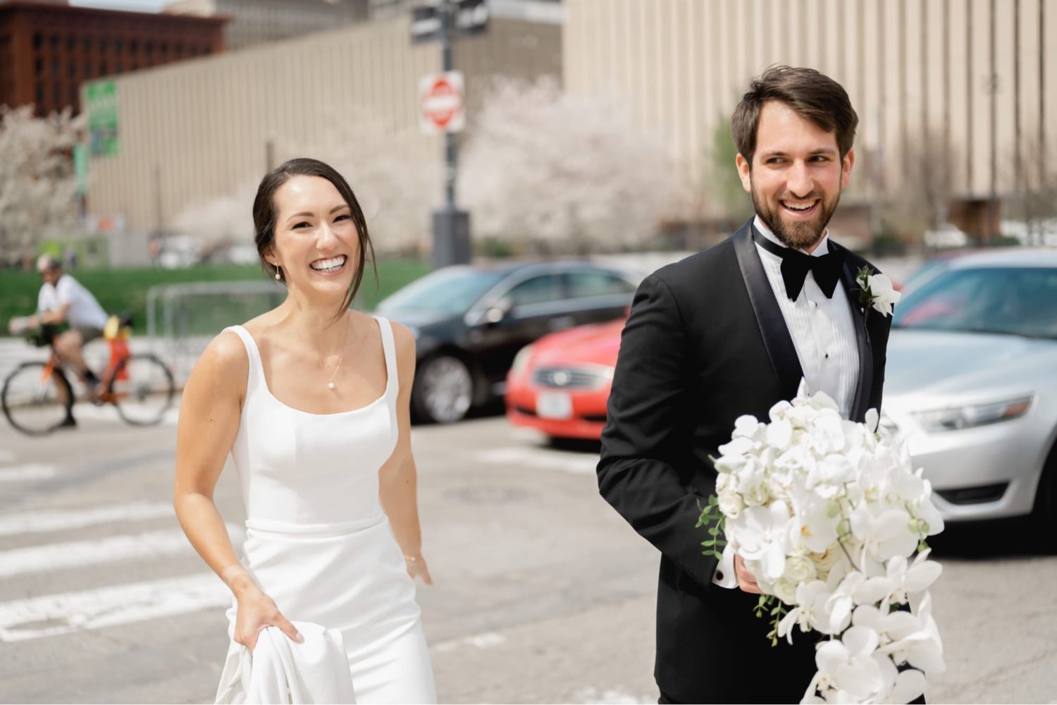 Bride and groom laughing walking across the street