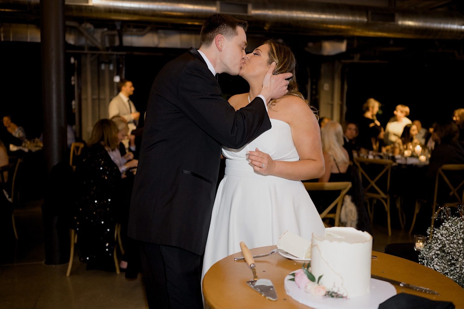 bride and groom kissing photo at cake cutting the river center