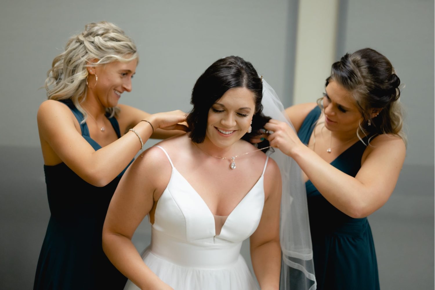 Bridesmaids helping bride put jewelry on at the Des Moines botanical Garden