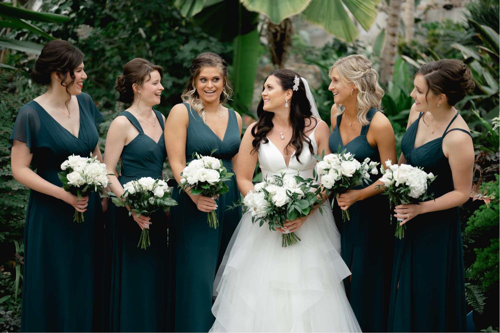 Bride and her bridesmaids smiling inside the Des Moines botanical center