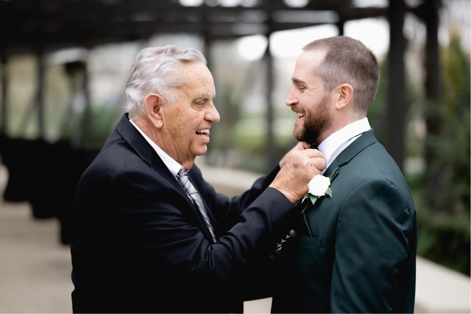 Father of the groom helping room straightened his tie