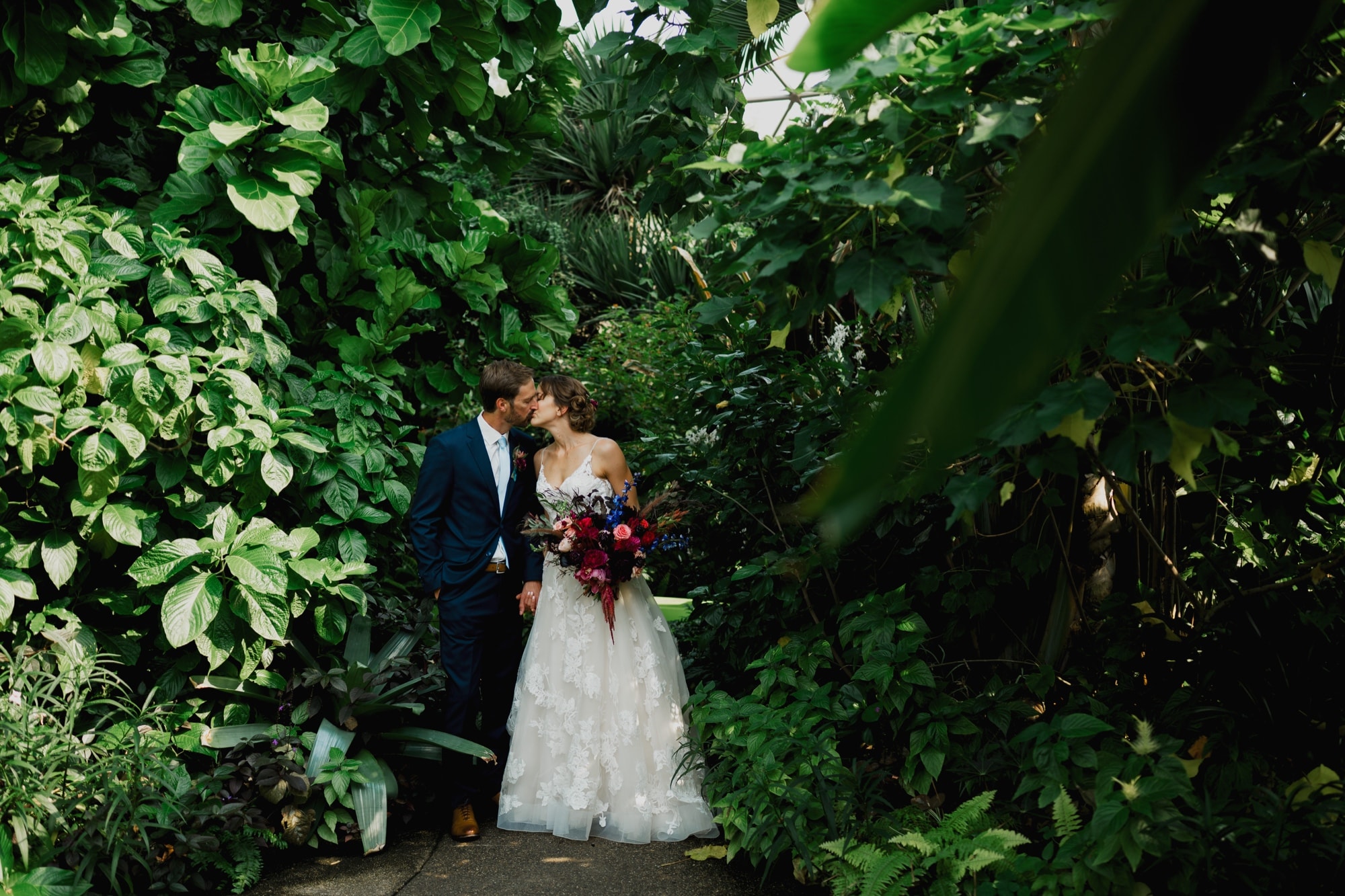 Bride and groom kissing in the greater Des Moines botanical Garden conservatory