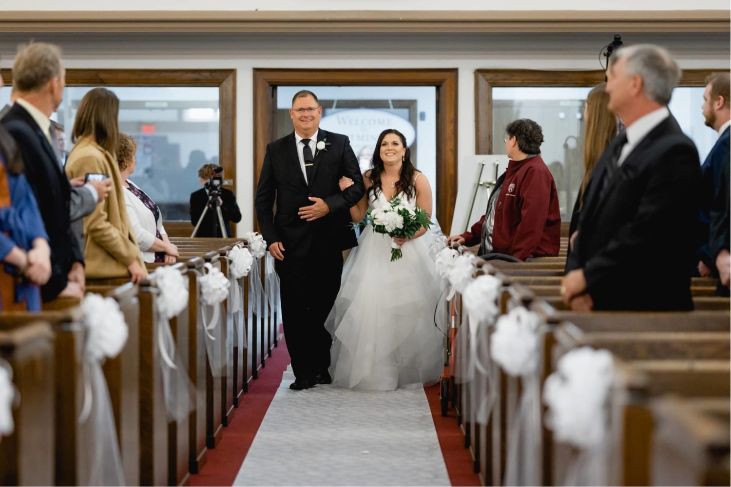 Bride being escorted down the aisle by her father at the wedding ceremony