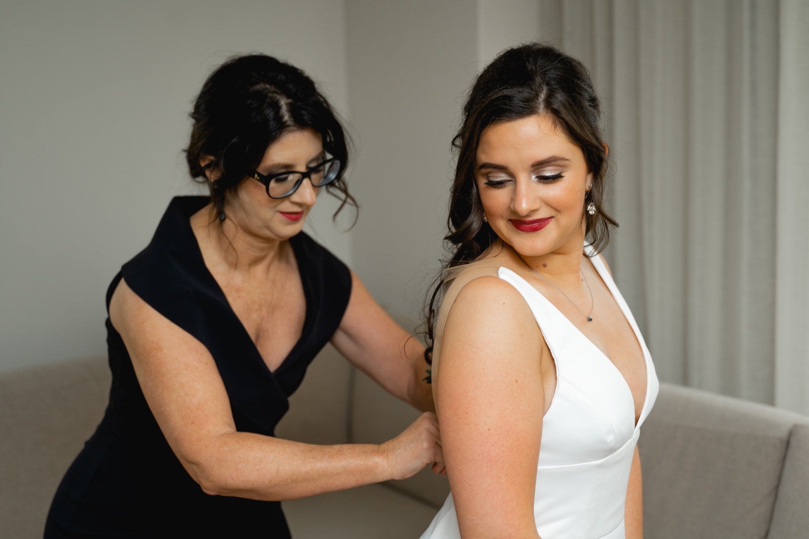mother helping bride into wedding dress at hotel fort des moines