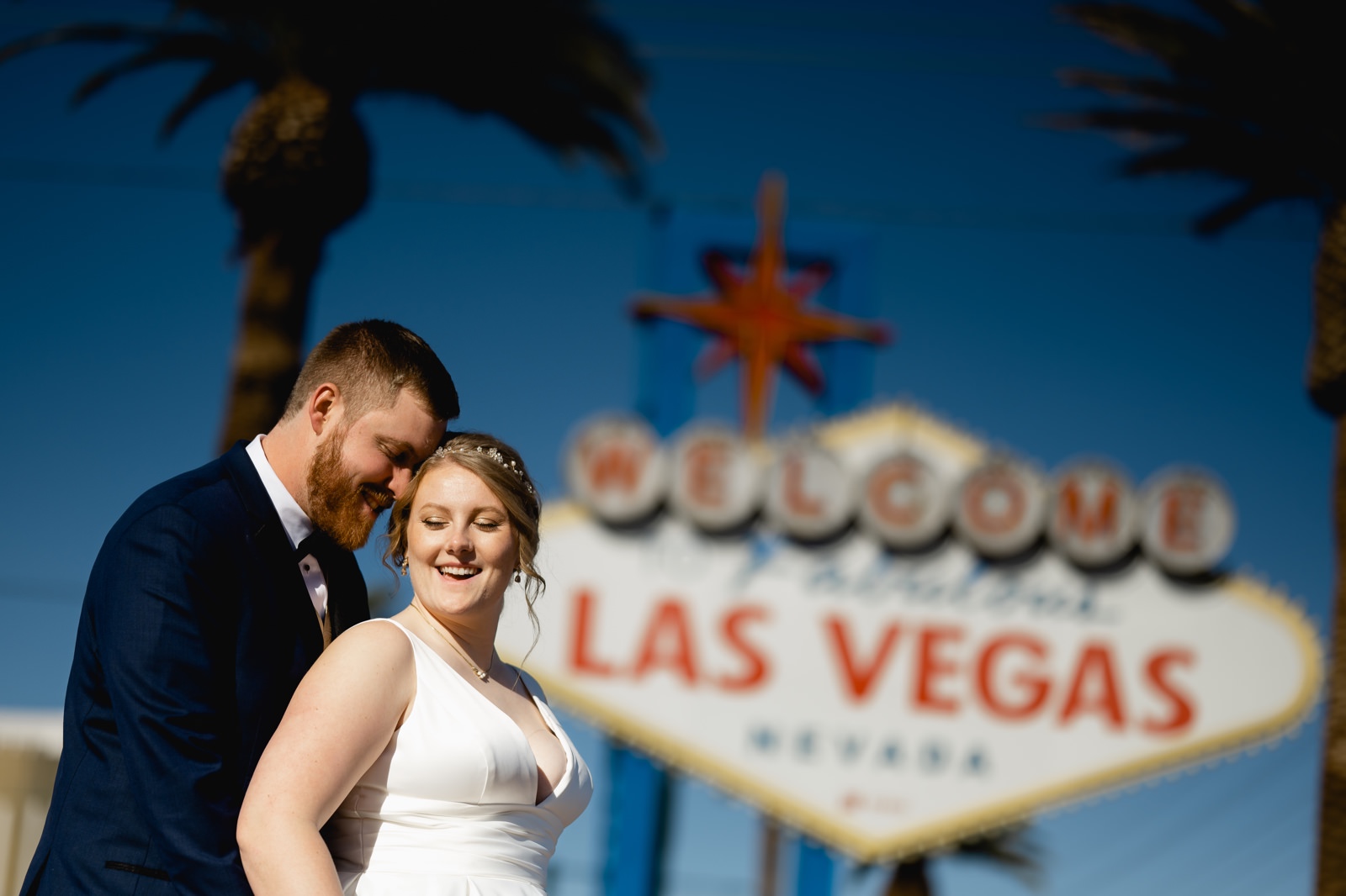 Bride and groom laughing at welcome to Las Vegas sign