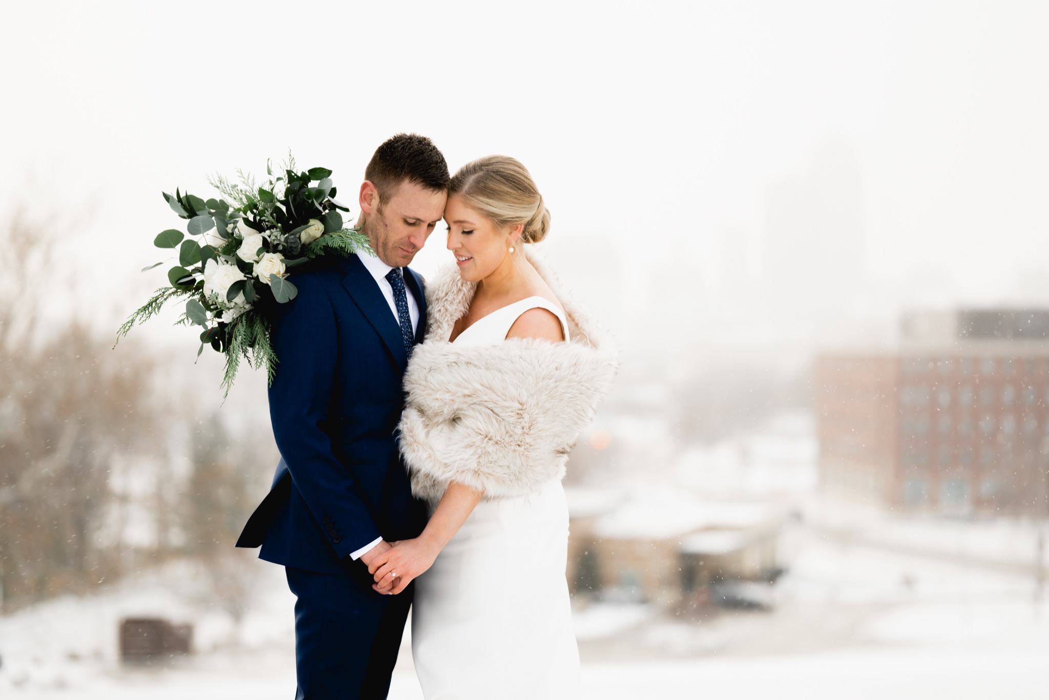 bride and groom overlooking the des moines skyline in the snow