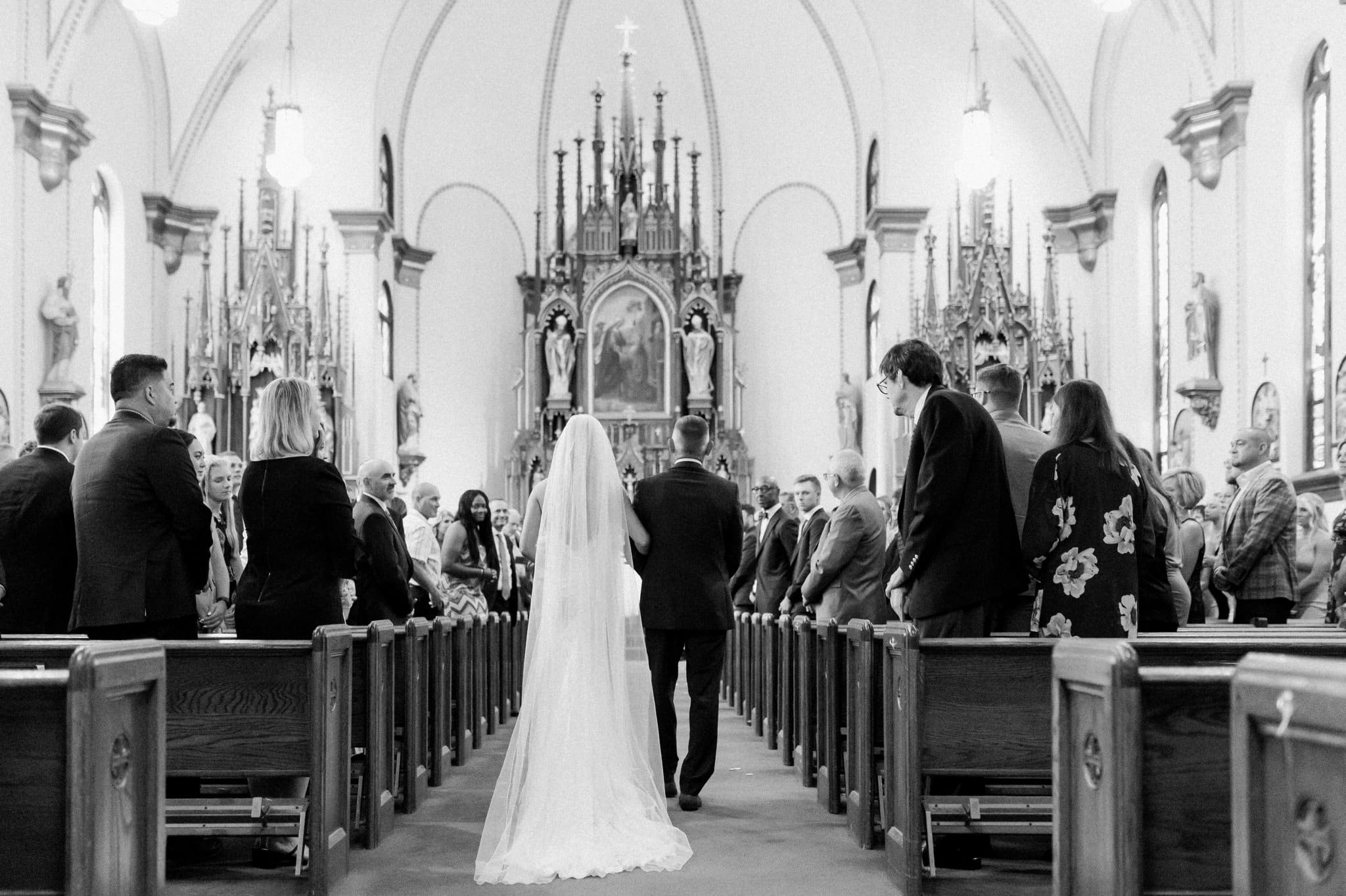 photo from behind of bride walking down the aisle with her dad iowa city wedding photographer