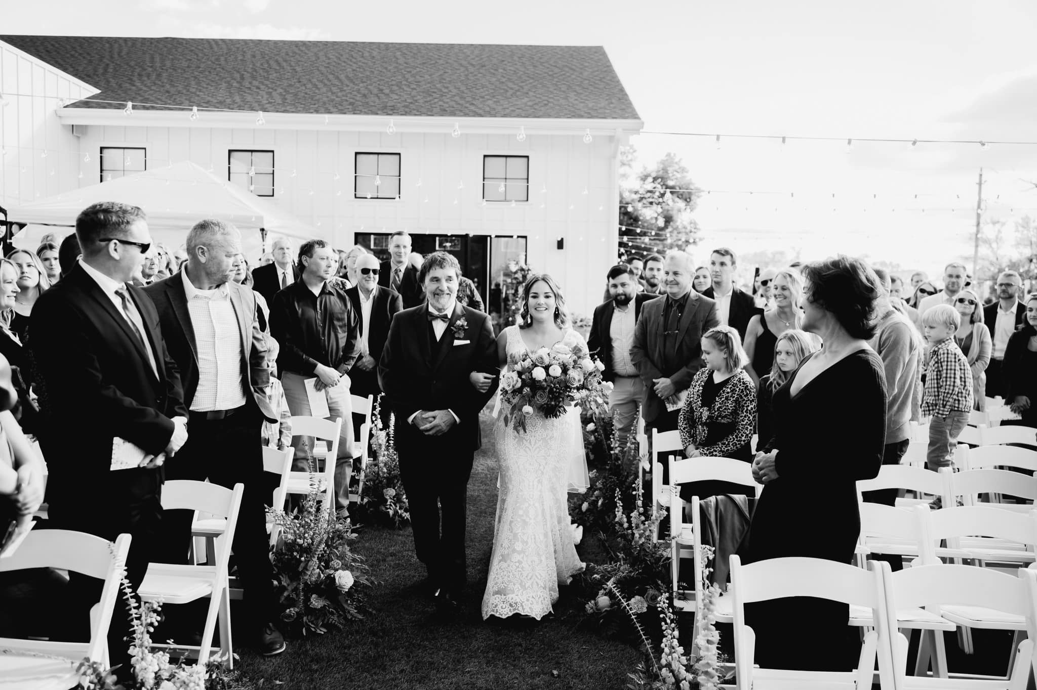 beautiful black and white photo of bride and father walking down the wedding aisle