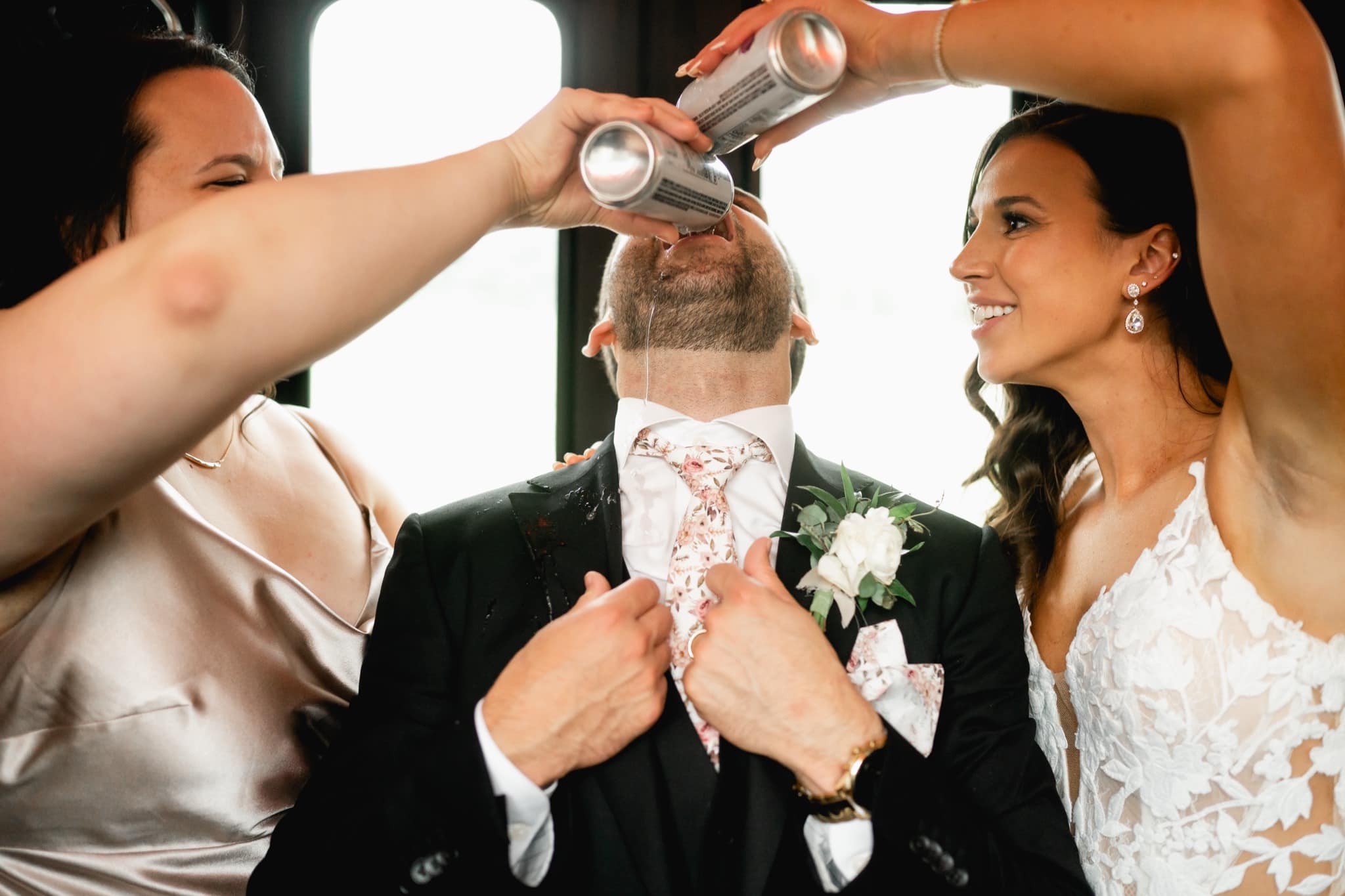 bride and bridesmaid pouring drink in groom’s mouth