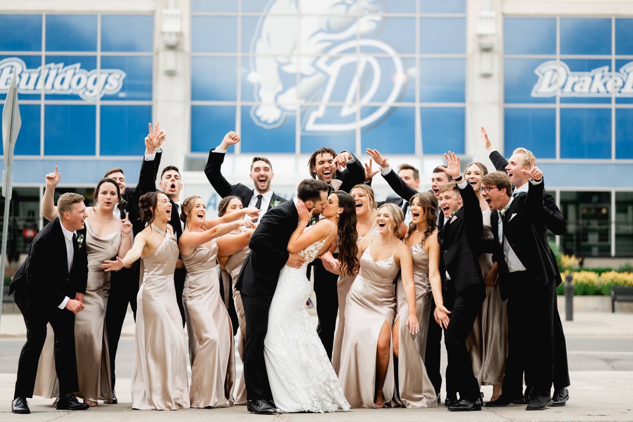 bride and groom celebrating with wedding party in front of drake university basketball arena